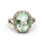 A diamond and aquamarine oval cluster white gold cocktail ring with diamond set split shoulders,