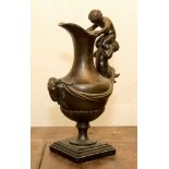 A bronze figural ewer on a marble base, the handle in the form of two putti,