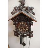 Black Forest carved wood cuckoo clock decorated in leaves and a bird finial with original weights