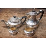 An Edwardian solid silver four piece tea set with gilt interior and ebony handles and finials,