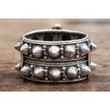 An Indian white metal bangle, with stud decoration,