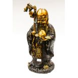 A Chinese bronzed and gilt metal figure of an elder holding a peach