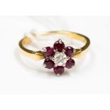 A ruby and diamond flower cluster ring, claw set central brilliant cut diamond of approx 0.