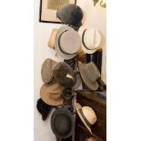 A collection of country house hats including grey top hat, riding hats, bowler, straw,