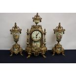 A brass mantle clock and garniture, the dial having Arabic numerals,