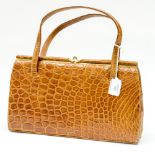 A circa 1950s tan coloured Crocodile skin handbag by Fassbender,