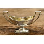 A George III silver two handled pedestal salt cellar, of Classical form, the interior gilt lined,