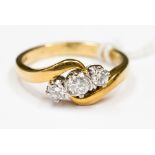 An 18ct diamond three stone ring, with a cross over band, set in 18ct yellow gold with white head,