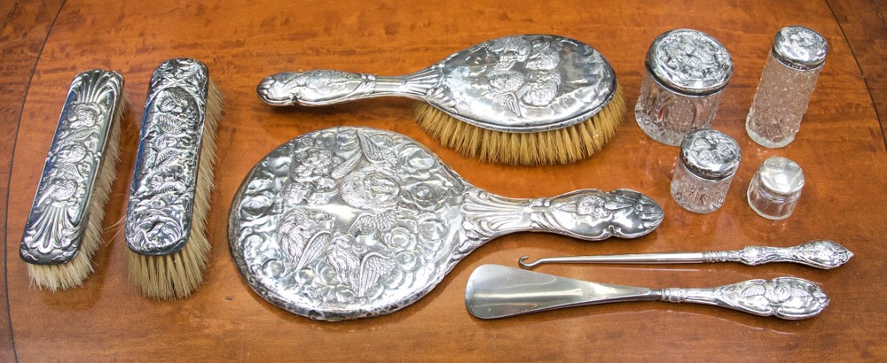 An Edwardian silver dressing table set, Reynolds Angels design, including silver topped jars,