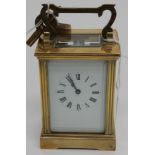 A late Victorian brass carriage clock, having a white enamelled dial, black Roman numerals,