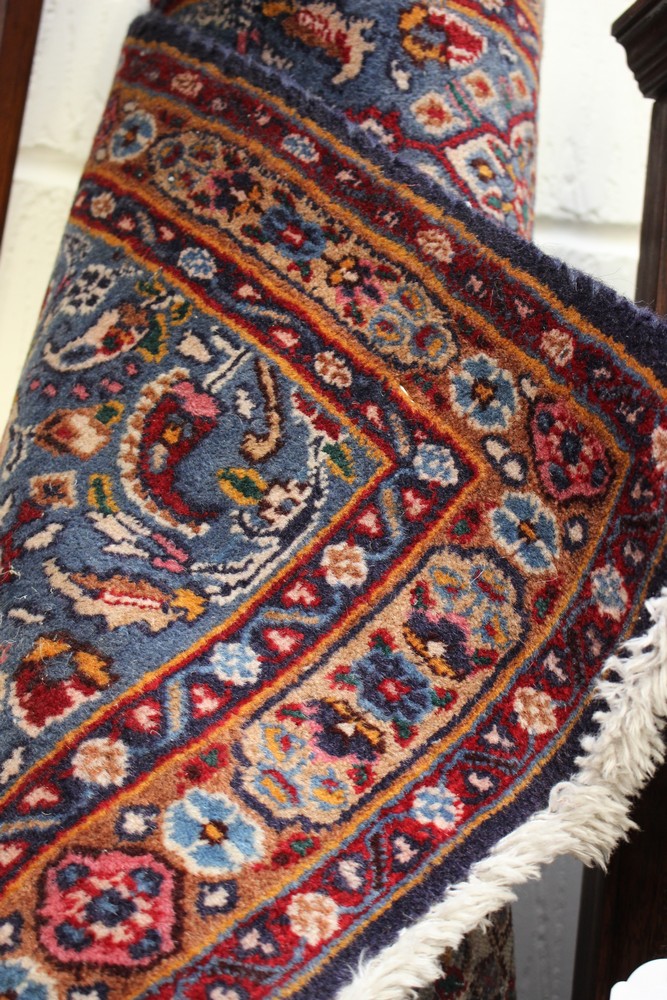 A Persian hand knotted woollen rug, with floral motifs on a red and blue ground with a blue border,