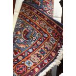 A Persian hand knotted woollen rug, with floral motifs on a red and blue ground with a blue border,