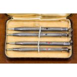 A set of four white metal bridge pencils, marked .