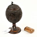 A late 19th century carved coconut shell, on carved hardwood plinth,