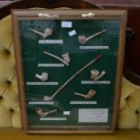 A well presented framed collection of eight reproduction English clay tobacco pipes on a green