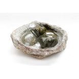 A soapstone carving of two Hippopotamus in a muddy pool, indistinctly signed,