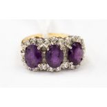 An 18ct gold ring set with three amethyst (damaged) surrounded by illusion set diamond chips,