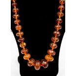 A graduated faceted amber bead necklace on white metal clasp,