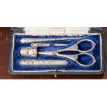 A cased white metal sewing kit,