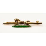 A 9ct gold bar brooch with a central galloping horse with an enamelled grass detail,