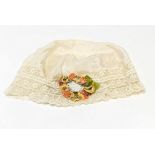 A silk bonnet dating to 1898-1900 with floral silk decoration.