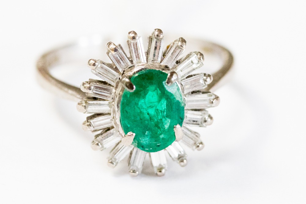 An emerald and diamond ring set in 18ct white gold, with an oval centre claw set diamond,
