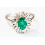 An emerald and diamond ring set in 18ct white gold, with an oval centre claw set diamond,