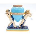 A 19th Century Majolica figural vase, the amphora shaped vessel supported by two putti,