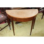 A George III mahogany demilune fold-over card table, with a cross-banded edge,