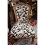 A mid Victorian walnut nursing chair, upholstered in floral fabric, standing on turned legs,