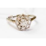 A diamond cluster ring, claw set central cushion cut diamond of approx 0.
