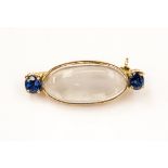 A moonstone and sapphire brooch in yellow metal,