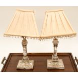A pair of Silver plated lamps with square base forms embossed with foliate and urn details,
