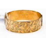 A 9ct gold bangle, hinged, with a width approx 20mm and a diameter of approx 60mm,
