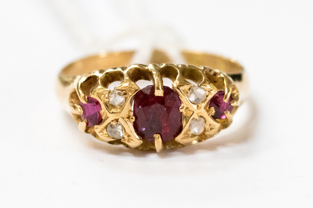 An 18ct ring set with three rubies and four diamond chips, size L1/2,