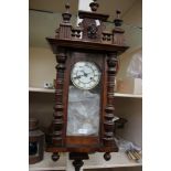 A mahogany carved eight day drop dial wall clock, enamelled dial with Roman numerals,