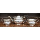 A three piece silver tea set comprising teapot with ebonised handle and finial, milk and sugar,