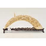 A Chinese carved walrus tooth, as a village bridge with figures trees and buildings,