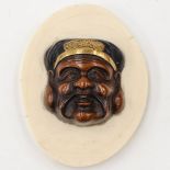 A Japanese carved wood head mounted on an ivory disc, Meiji,