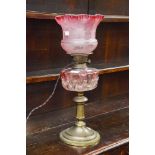 A converted Cranberry glass and brass oil lamp