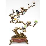 A bronzed metal and porcelain three light candelabra modelled as flowering bonsai trees with birds