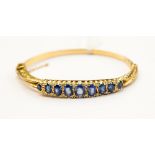 A sapphire and diamond set 18ct gold hinged bangle,