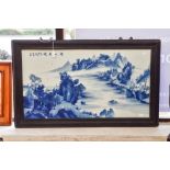 A framed Chinese ceramic plaque, handpainted in blue and white with mountains and lake scene,