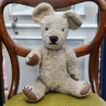 A mohair teddy bear, circa 1930's, grey beige, with stitched claws and button eyes.