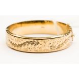 A 9ct gold hinged bracelet engraved to the front leafage scrolls,