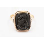 A gold ring inset with carved onyx set in yellow metal probably 18ct.