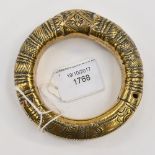 A brass Middle Eastern bangle, possibly Indian, engraved throughout,