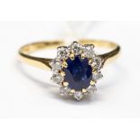 A sapphire and diamond oval cluster 18ct gold ring, centre oval blue sapphire approx 5.7mm x 4.