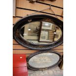 An early 20th Century black lacquered oval wall mirror,