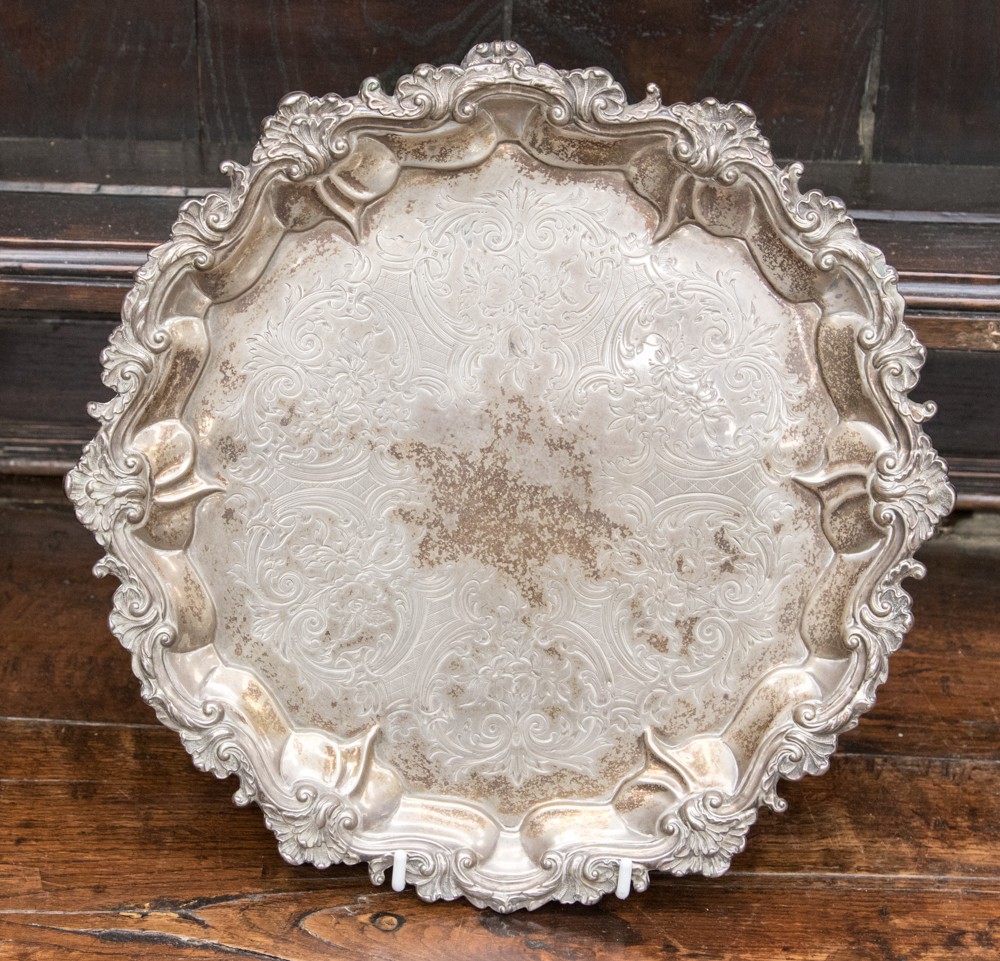 A silver footed salver having raised foliate pattern around the rim,